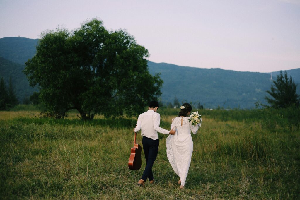 A newlywed couple walking hand in hand in a scenic field in Da Nang, Vietnam.